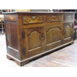 A Georgian oak dresser enclosed by a pair of doors with arched and fielded panels with three