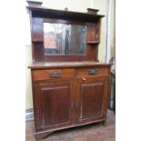 An arts and crafts oak cottage dresser enclosed by a pair of panelled doors and two frieze