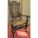 A Carolean style elbow chair in walnut, the well carved frame supporting a cane panelled seat and