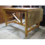 A stripped pine drop-leaf kitchen dining table with rectangular top raised on square cut and