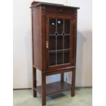 A 1920s Jacobean revival oak side cabinet enclosed by a rectangular leaded light panelled door,