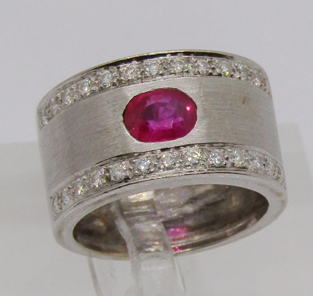 18ct white gold band ring set with an oval ruby and two rows of diamonds, size K/L, 8.9g