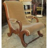 A Victorian mahogany nursing chair with scrolled outline, open arms and upholstered seat