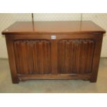 A small reproduction oak coffer/blanket chest in the Old English style with hinged lid over a