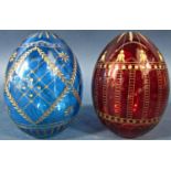A red cut glass Faberge style Easter egg with a repeating gilded design and another dark green