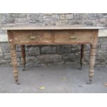 An Edwardian scrubbed pine writing table fitted with two frieze drawers raised on turned tapered