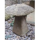 A weathered cast composition stone staddle stone and cap, 58 cm high, together with a similar