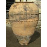 An old weathered terracotta ovi-form olive jar with thumb pressed bands, 74cm high