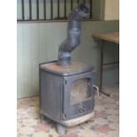 A Morso cast iron wood burning stove enclosed by a partially glazed panelled door