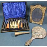 A silver peacock embossed hand mirror, a silver photo frame, silver handled fruit knives and forks