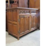 A Gothic revival oak side cupboard enclosed by a pair of linen fold panelled doors with decorative