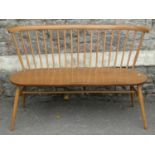 An Ercol light elm and beechwood loveseat/bench the raised simple stick back with curved moulded