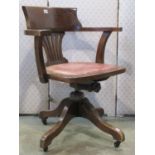 An early 20th century oak swivel office desk chair with comb splat over upholstered leather pad seat