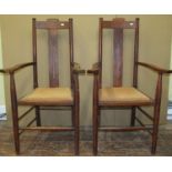 A pair of arts and crafts elbow chairs in oak with pierced splats, upholstered seats, on turned