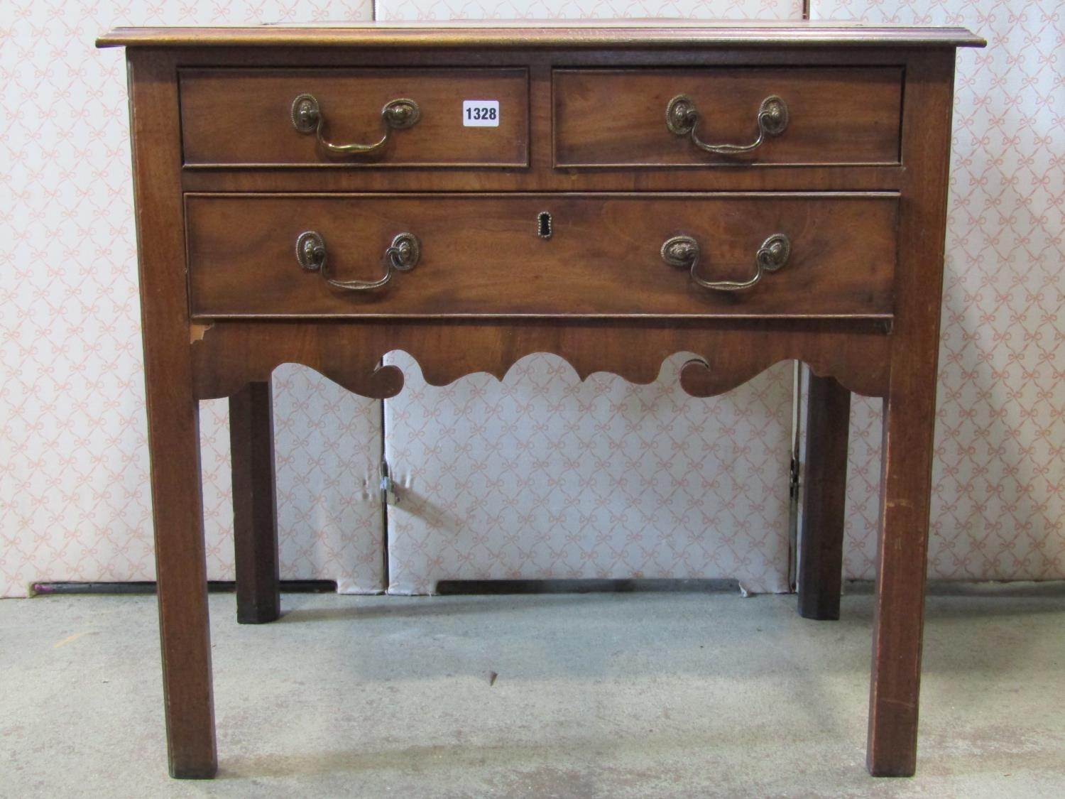 A Georgian mahogany lowboy of one long and two short drawers with shaped apron, raised on square cut