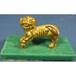 A gilded temple lion with foreleg upon a ball on a green stone plinth, 11cm long
