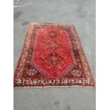 A large Persian carpet with three interlocking central medallions with stylised birds and flowers on