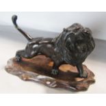 A bronze Japanese Meiji period lion roaring, with makers stamp to the belly, placed on a wooden