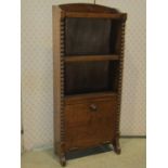 A small 1920s oak freestanding open bookcase partially enclosed by a lower fall front