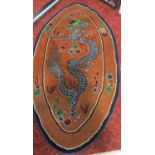An oval Tibetan rug with a blue dragon with a green head on an apricot ground 145cm x 78cm approx