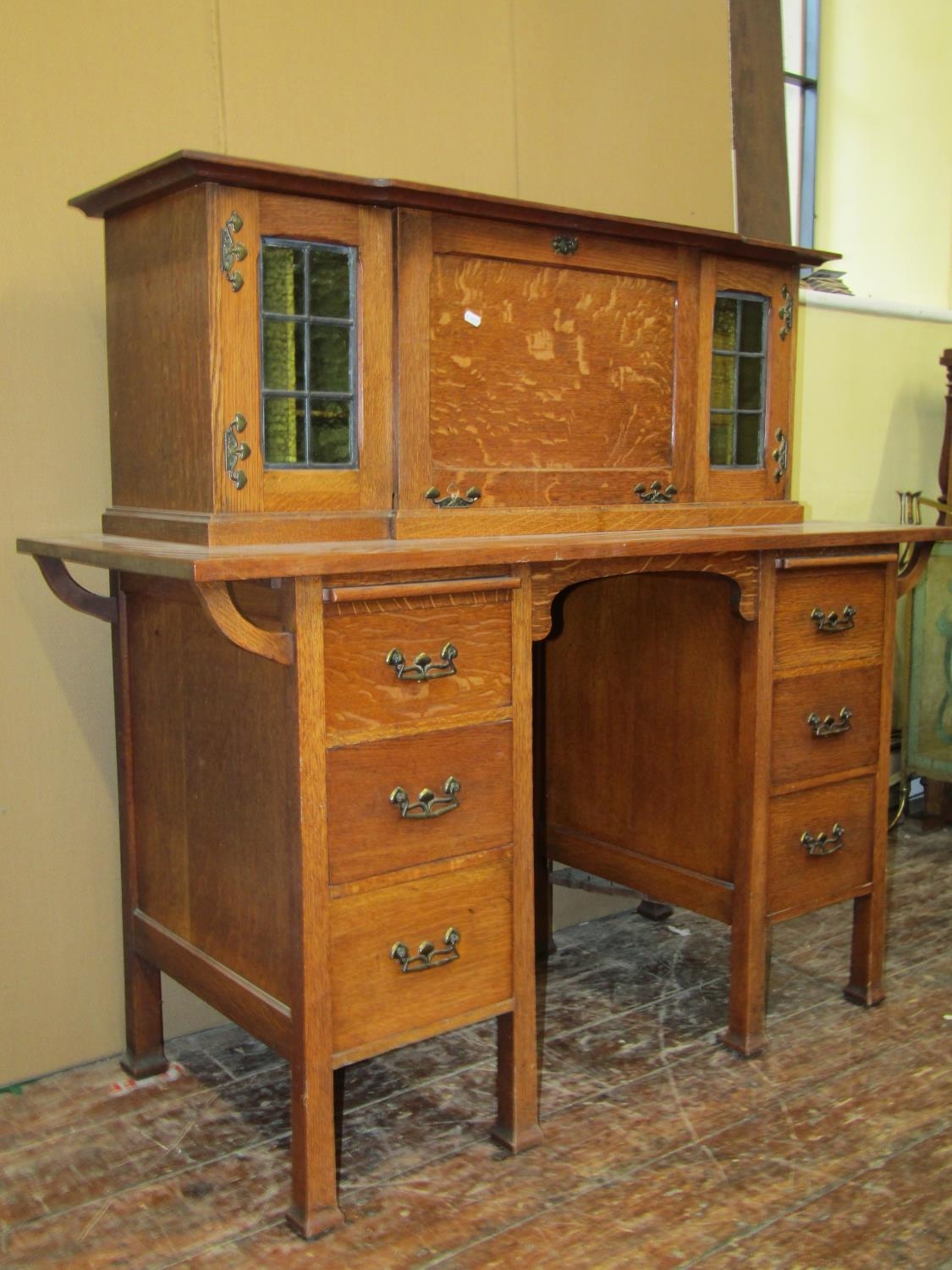 An arts and crafts oak writing desk - Stone's Patent, the lower section fitted with six drawers