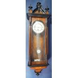 A 19th century Vienna style wall clock within a walnut case with applied ebonised detail,