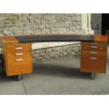 A 1970s teak office desk with unusual curved top incorporating a writing surface set on twin