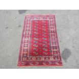 A Bokhara rug with two row of elephant foot medallions on a predominantly red ground, 130cm x 80cm