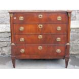 A French Empire period chest of four long drawers, set within turned column supports, with gilt