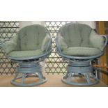 A pair of sprung cane work swivel lounge chairs with loose cushions and later painted finish