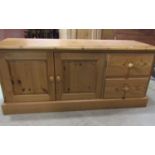 A low stripped pine side cupboard enclosed by a pair of square fielded panelled doors and two