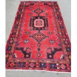 North east Persian Kurdie rug with an extended hooked medallion and a geometric border on a red