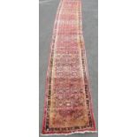 A Hamadan runner with a repeating geometric pattern on a predominantly pink ground, 500cm x 88cm.