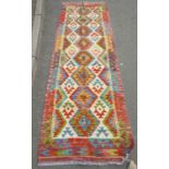 A Chobi kilim runner with continuous fetter motif design in multicoloured tones, 257cm x 83cm approx