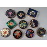 A collection of ten vintage compacts, the majority by Stratton, with floral themes, upon a dark blue