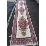 A Middle Eastern Runner with three central medallions and scrolling floral motifs in pink on an