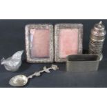A silver napkin ring, a silver pepper pot, a teaspoon with flower handle, two miniature photo