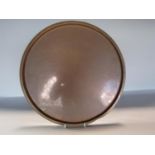An arts and crafts copper circular charger with a simple engraved apple design to the centre,