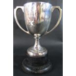 A silver double handled trophy cup engraved with dedication, raised on wooden base, cup 18 x 18cm