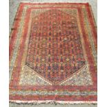 An old Persian rug with repeated central diamond boteh design and animal motifs in tones of crimson,