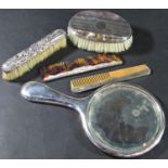 A silver hand mirror, two silver mounted combs and two silver backed brushes