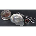 A silver scallop dish, 14 x 11cm approx, a silver wine coaster, a small napkin ring and a pair of