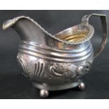 A Georgian silver cream jug, floral embossed and engraved, raised on four ball supports, London