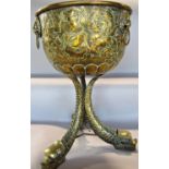 A 19th century Regency brass embossed punch bowl with lion mask handles, raised on three swept