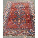 A Middle Eastern Rug with triple pole medallion on a madder field of floral and animal motifs, and