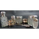 A varied collection of silver comprising five silver capped glass jars, salt and mustard pots and