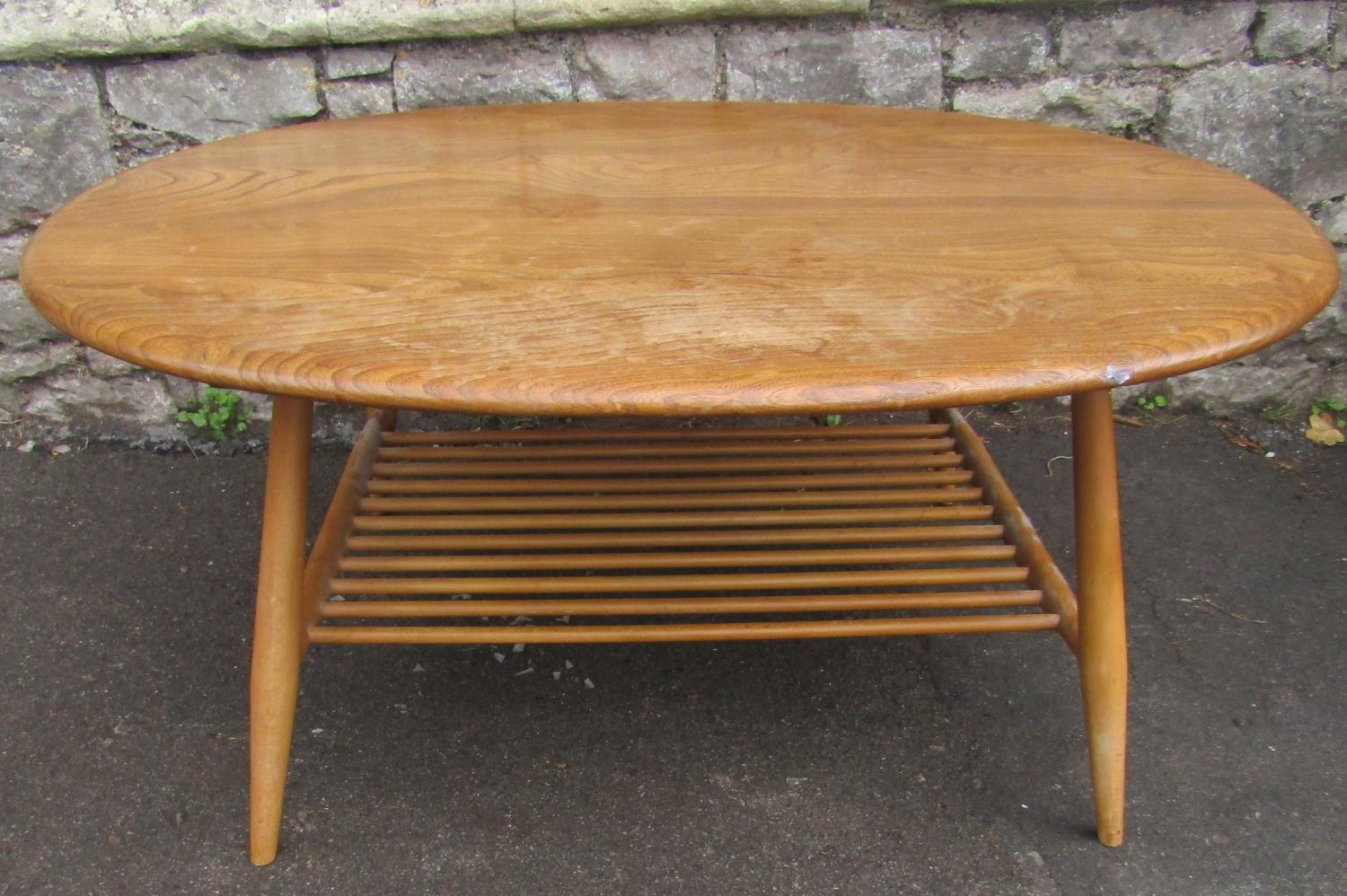 A vintage Ercol elm and beechwood occasional table of oval form raised on simple turned tapered legs