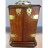 A Victorian oak brass bound smoker’s cabinet with a hinged top and double opening doors opening to