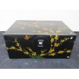 A Chinese black lacquered trunk with hand painted prunus blossom detail, 80cm long x 55cm deep x