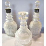 A pair of 1920’s diamond cut glass decanters with silver collars, and third smaller decanter with